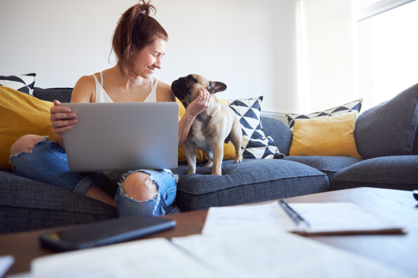 woman on couch working on laptop beside dog | Write Faster, Earn More: Confronting Writer’s Block