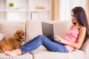 woman sitting on couch with dog working on laptop | How to Use Canva Templates for Your Small Business