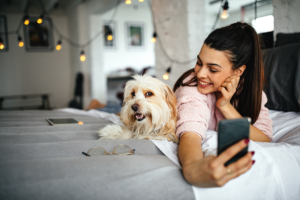 woman taking selfie on bed with a dog | 9 Instagram Reels Ideas for the Pet Business