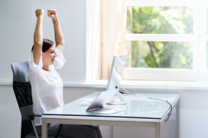 woman celebrating in front of computer with arms in the air | How Part-Time Bloggers Can Get More Done