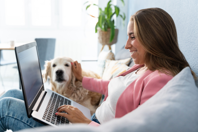 woman working on laptop on the couch with a dog | 8 Steps for Creating an Action Plan to Achieve Your Goals