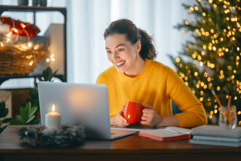 woman working on laptop surrounded by Christmas decor | 7 Tips for Using the Holiday Break to Prepare for the New Year as a Small Business Owner