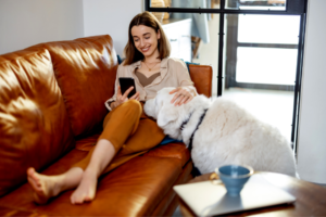 woman petting dog and using phone on couch | Instagram for Business Growth: Vanity Metrics Vs Actionable Metrics