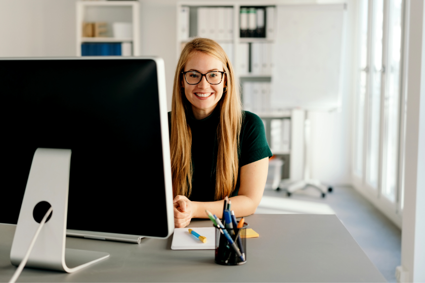 woman smiling and working at a computer | How to Set Yourself Up for Inbound Marketing Success in 2024