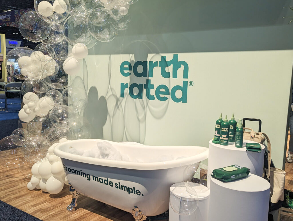 Booth display at the Earth Rated booth featuring a clawfoot tub, balloons, and grooming products