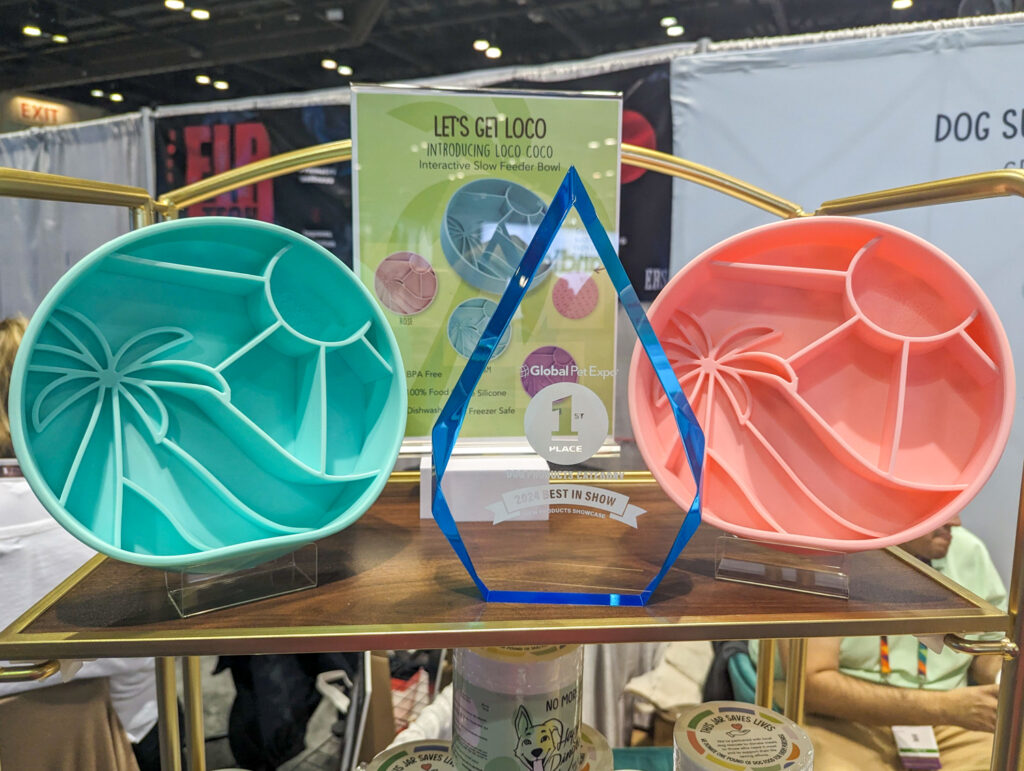 Two Let's Get Loco Slow Feeders (one in pink and one in teal) next to New Product Showcase Best in Show Award