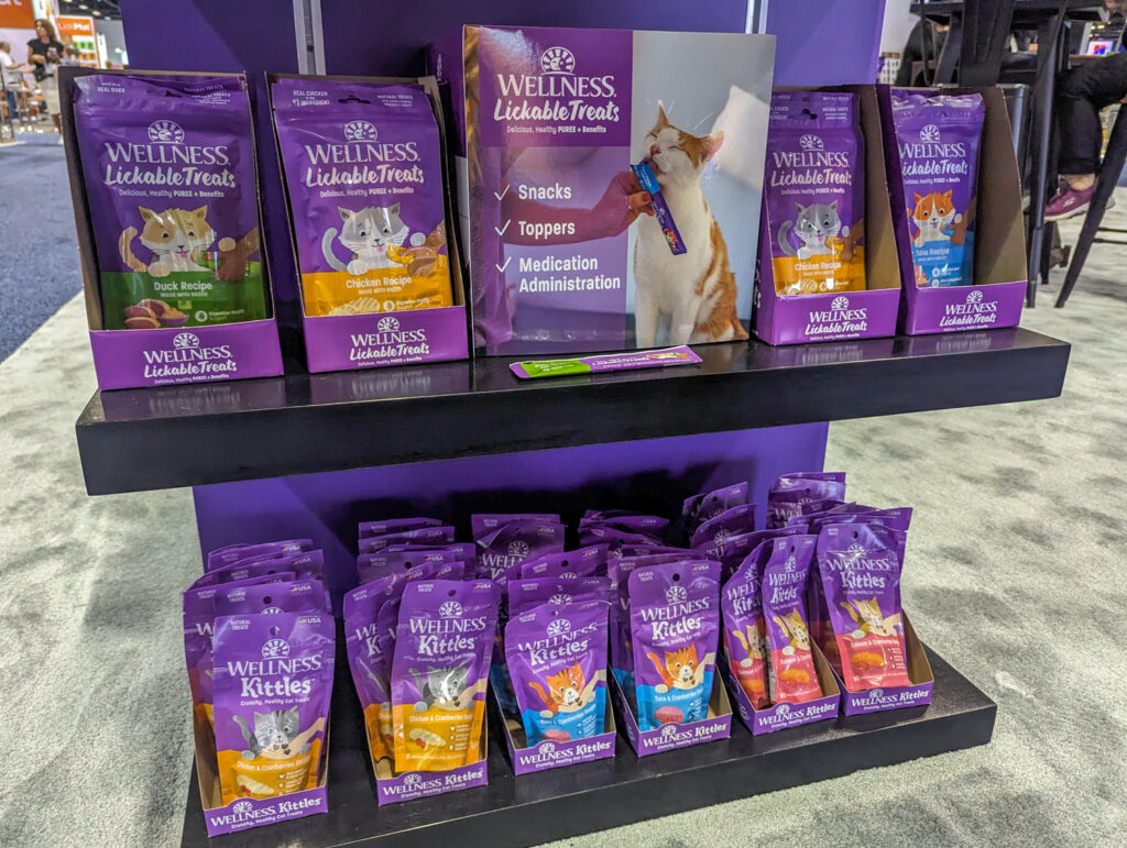 Purple packages of Wellness Lickable Treats and Wellness Kittles on display