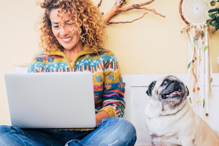 woman working on a laptop sitting next to a pug | Tips To Share Your Brand Story On Your About Page