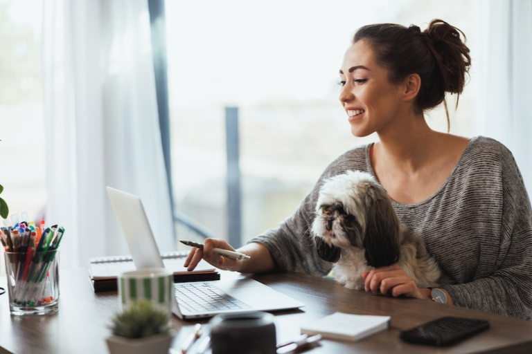 woman working on a laptop with a dog in her lap | Most Important Google Analytics Metrics for Bloggers and Content Creators